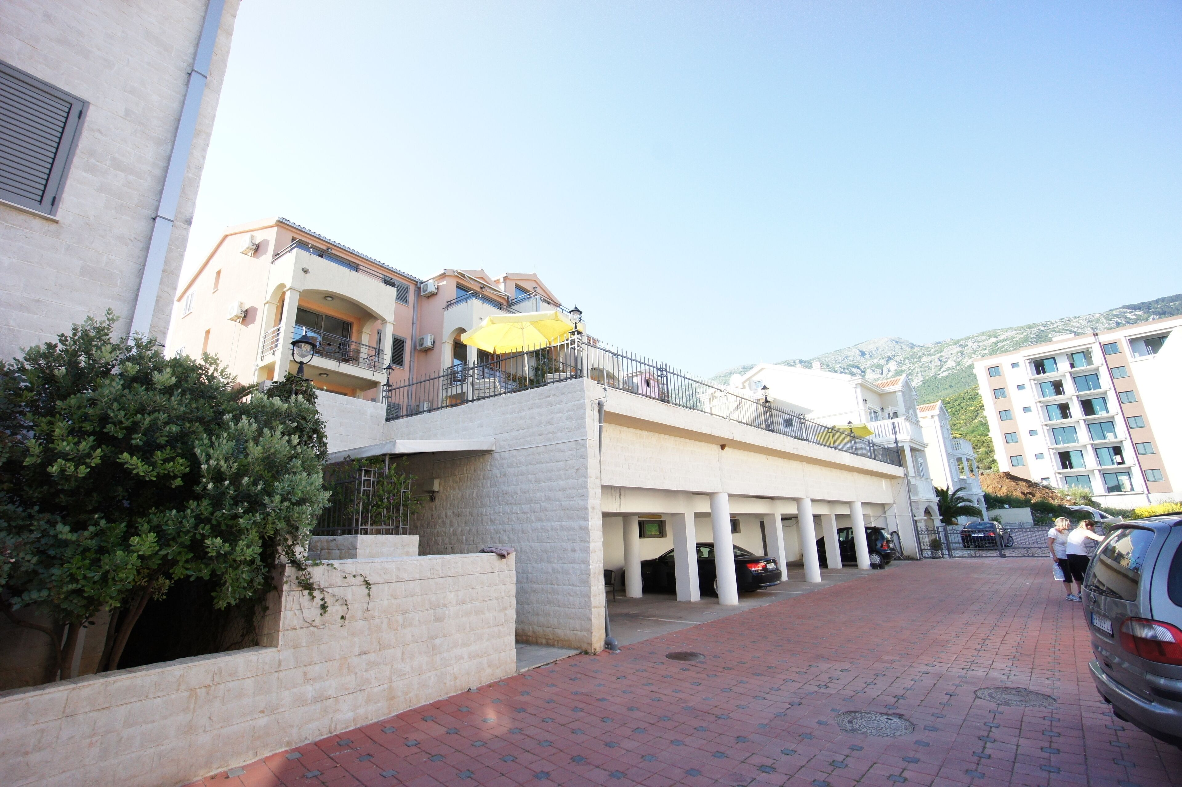 A building with a balcony, a yellow umbrella, and a parking area.