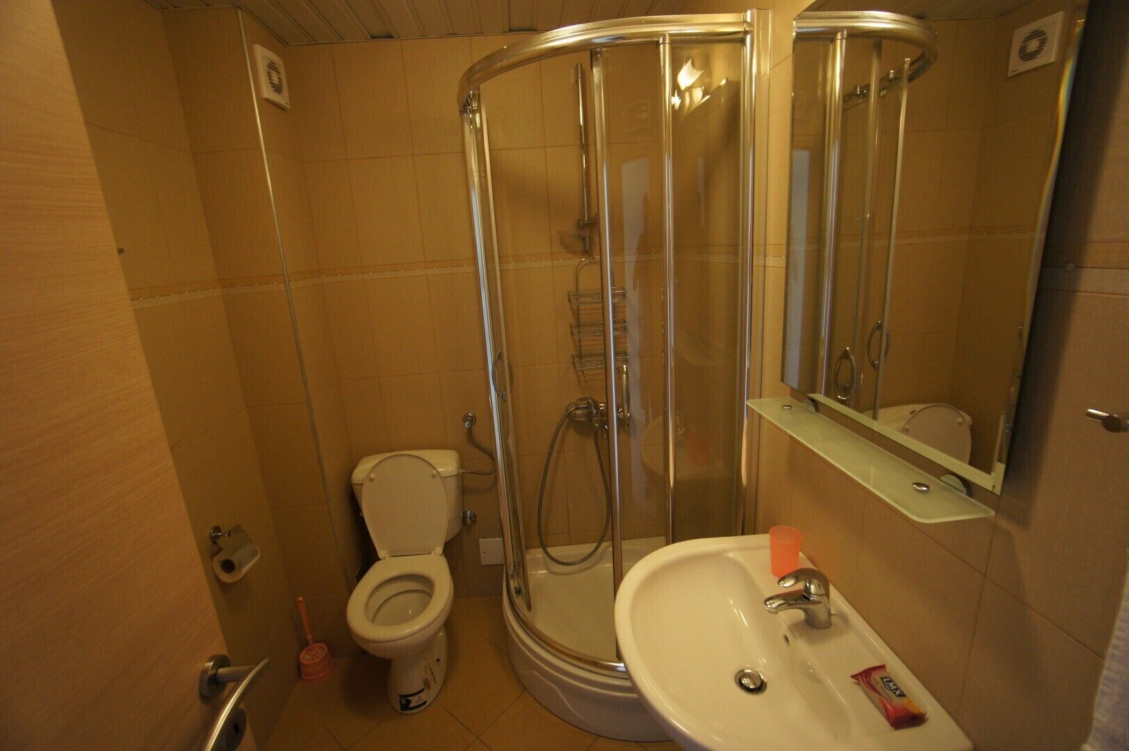 A bathroom with a toilet, a shower enclosure, and a sink.