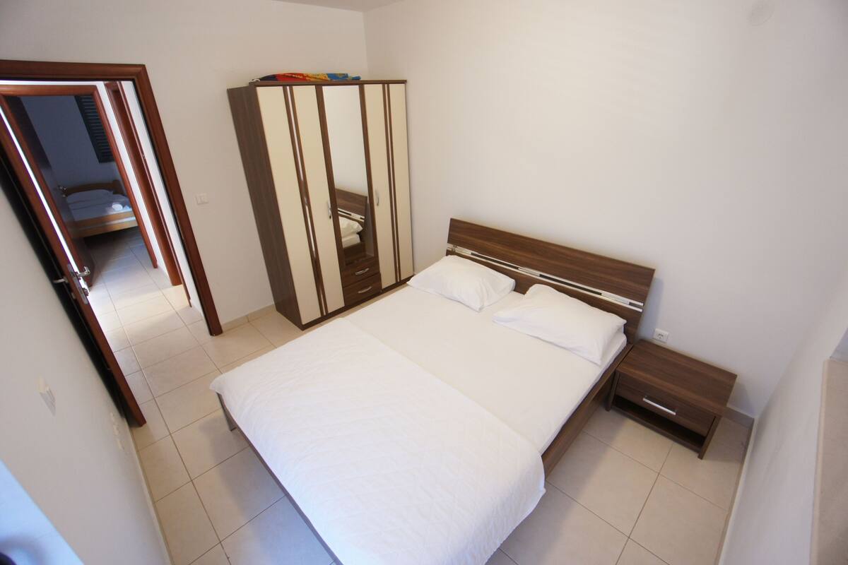 A bedroom with a bed, a wardrobe, and a nightstand.