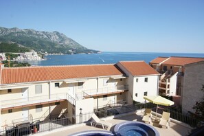 A hotel with a pool, outdoor seating, and a view of the sea and mountains. - Apartments Becici Sunset (Becici)