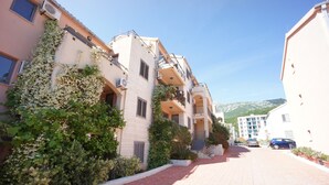 A residential street with multi-story buildings, a paved walkway, and parked cars.