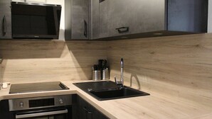 A modern kitchen with a stainless steel microwave, oven, and black sink. - Ski-In/Ski-Out Apt, 2 Rooms, Mountain Corner, Sleeps 4, Central Vars, Near Slopes & Shops (Vars)