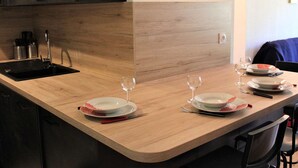 A kitchen with a wooden countertop, a black sink, and a dining area with a table set for two. - Ski-In/Ski-Out Apt, 2 Rooms, Mountain Corner, Sleeps 4, Central Vars, Near Slopes & Shops (Vars)