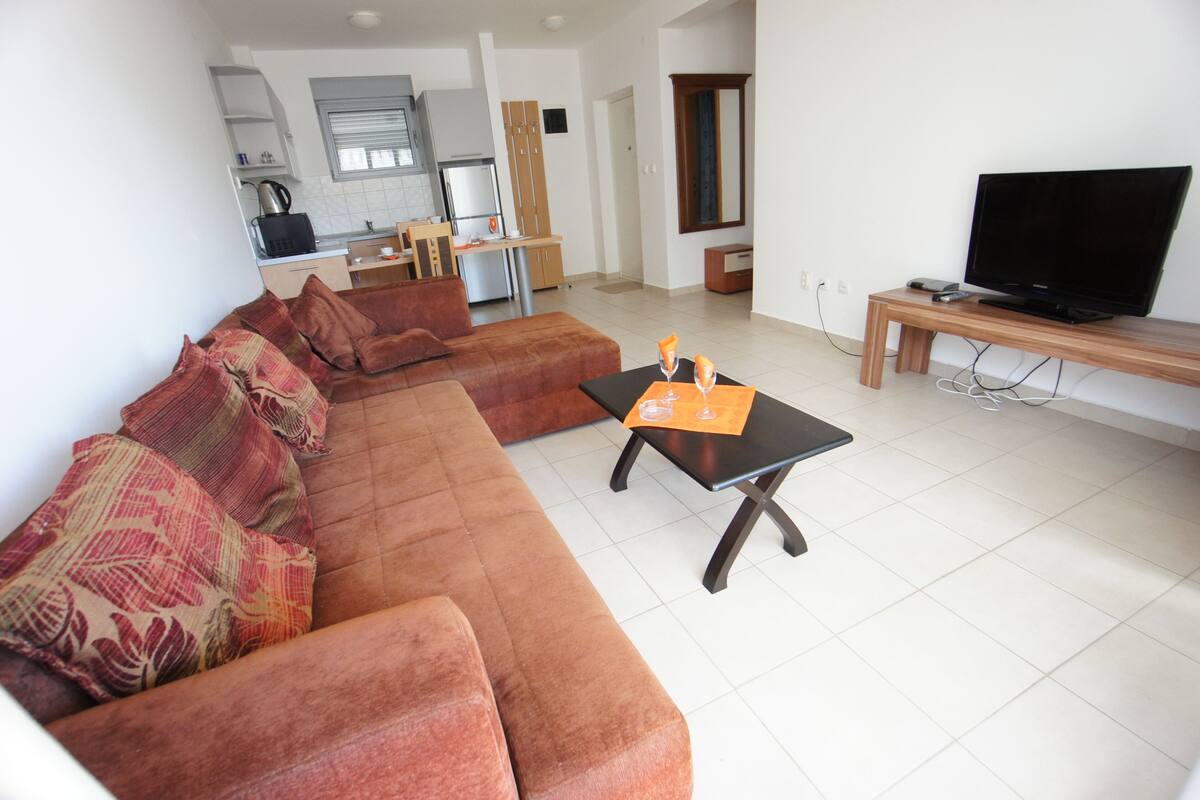 Una sala de estar con un sofá, una mesa de centro y un televisor sobre un mueble.