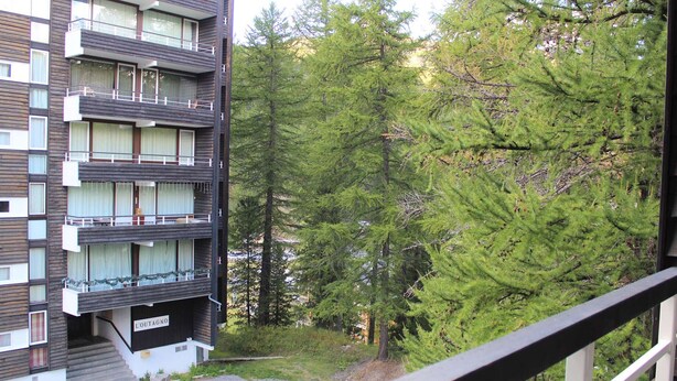 A multi-story building with balconies, surrounded by dense forest. - Studio for 4 in the heart of Vars Les Claux (Vars)