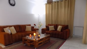 Ein Wohnzimmer mit zwei braunen Sofas, einem Couchtisch aus Holz mit Kerzen und einem gemusterten Teppich.