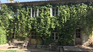 A building with ivy-covered walls, a patio with metal chairs and tables, and a stone pathway leading to the entrance. -  Commanderie de Peyrassol (Flassans-sur-Issole)