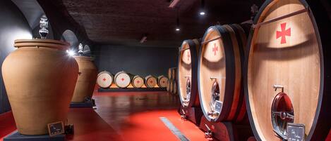 Una bodega con barriles de madera grandes y un piso rojo.
