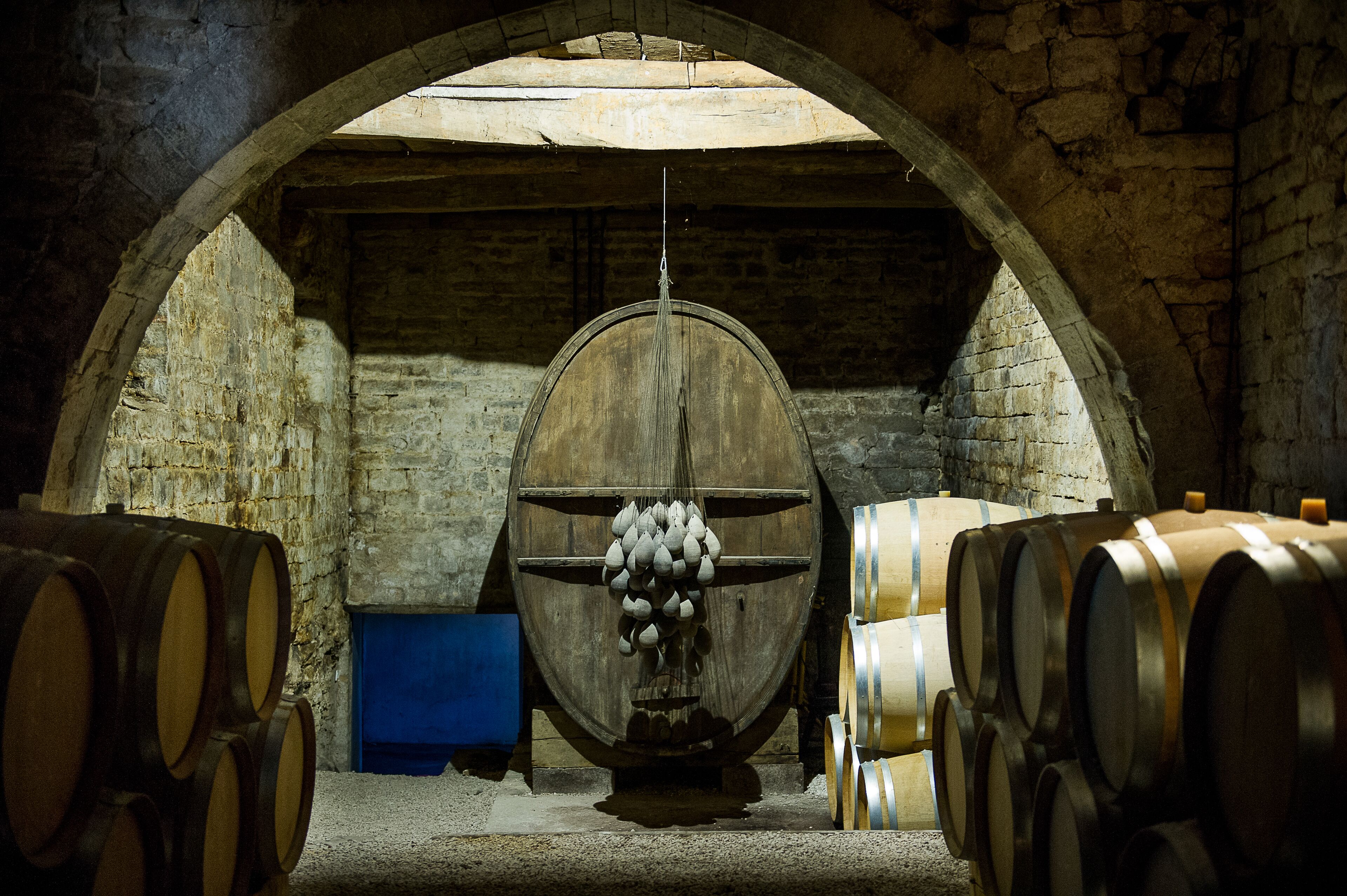 A wine cellar with wooden barrels and a large barrel in the center.