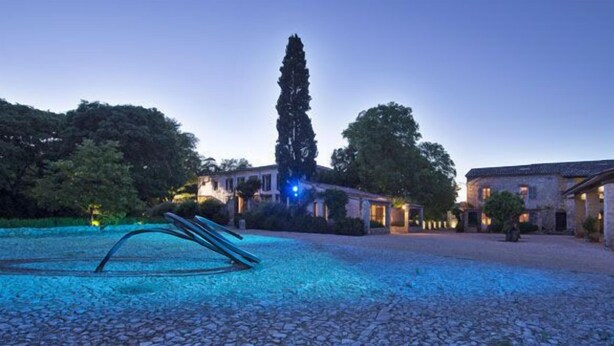 A courtyard with a pool, stone pathway, and buildings with warm lighting. -  Commanderie de Peyrassol (Flassans-sur-Issole)