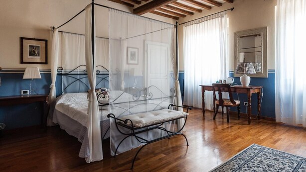 Ein Schlafzimmer mit einem Himmelbett, einem Holztisch, einem Stuhl und einem Spiegel.