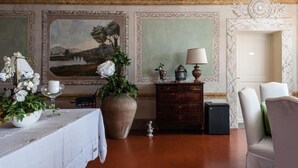 Ein Tisch ist für das Essen gedeckt, eine große Vase mit Blumen, eine Lampe und ein Gemälde an der Wand.