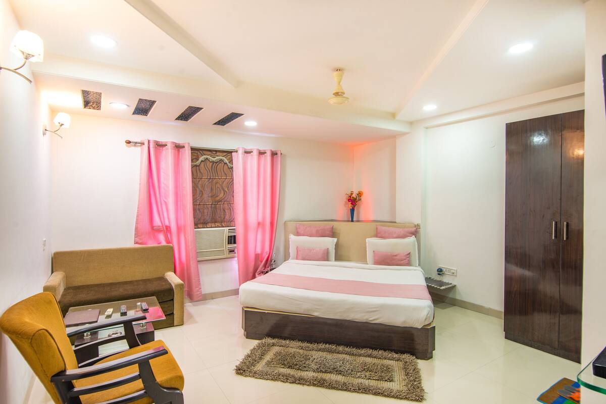 A bedroom with a bed, a sofa, a chair, a nightstand, and a wardrobe.