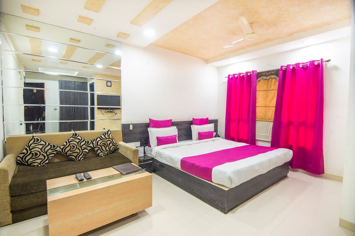 A modern bedroom with a bed, a sofa, a glass coffee table, and a mirror.