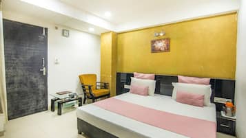 A hotel room with a bed, a chair, a small table, and a door.
