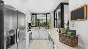 A modern kitchen with stainless steel appliances, a built-in oven, and a large window providing a view of greenery outside.