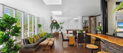 A modern interior with a wooden floor, a bar area, and a seating area with a sofa and chairs.