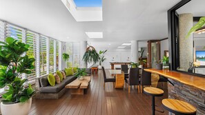 Ein modernes Interieur mit Holzboden, einer Bar und einer Sitzecke mit Sofa und Sesseln.