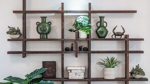 Une étagère en bois ornée d’objets décoratifs, notamment des vases, une plante en pot et des livres.