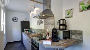 Ett modernt kök med en central köksö, rostfria vitvaror och en klocka på väggen.