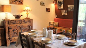 Un coin repas avec une table dressée pour quatre personnes, des chaises en bois, une lampe ancienne et un meuble agrémenté de poignées décoratives.