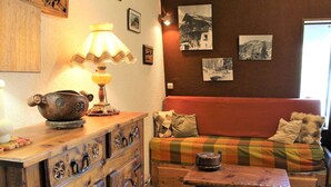 Un salon chaleureux avec un meuble en bois, une table, un canapé et une lampe.