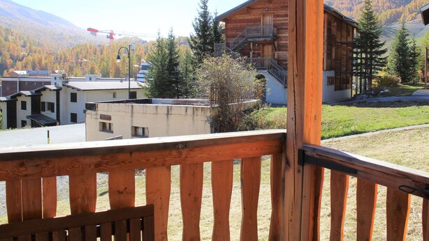 Une cabane en bois dotée d’un balcon donnant sur un paysage montagneux.
