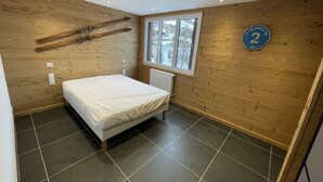 Una camera da letto con un letto, pareti in legno, una finestra e un cartello con il numero 2.