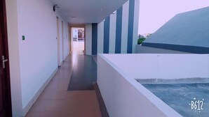 Un couloir doté d’un sol carrelé, de murs blancs et de rayures verticales bleues.