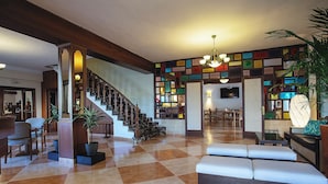 A spacious lobby with a checkered floor, a staircase, and a seating area with a sofa and chairs. - Hotel Ses Puntetes (Santanyi)