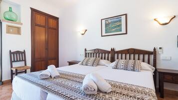 Ein Hotelzimmer mit einem großen Bett, zwei Nachttischen, einem Holzschrank, einem Sessel und einem Bild an der Wand.