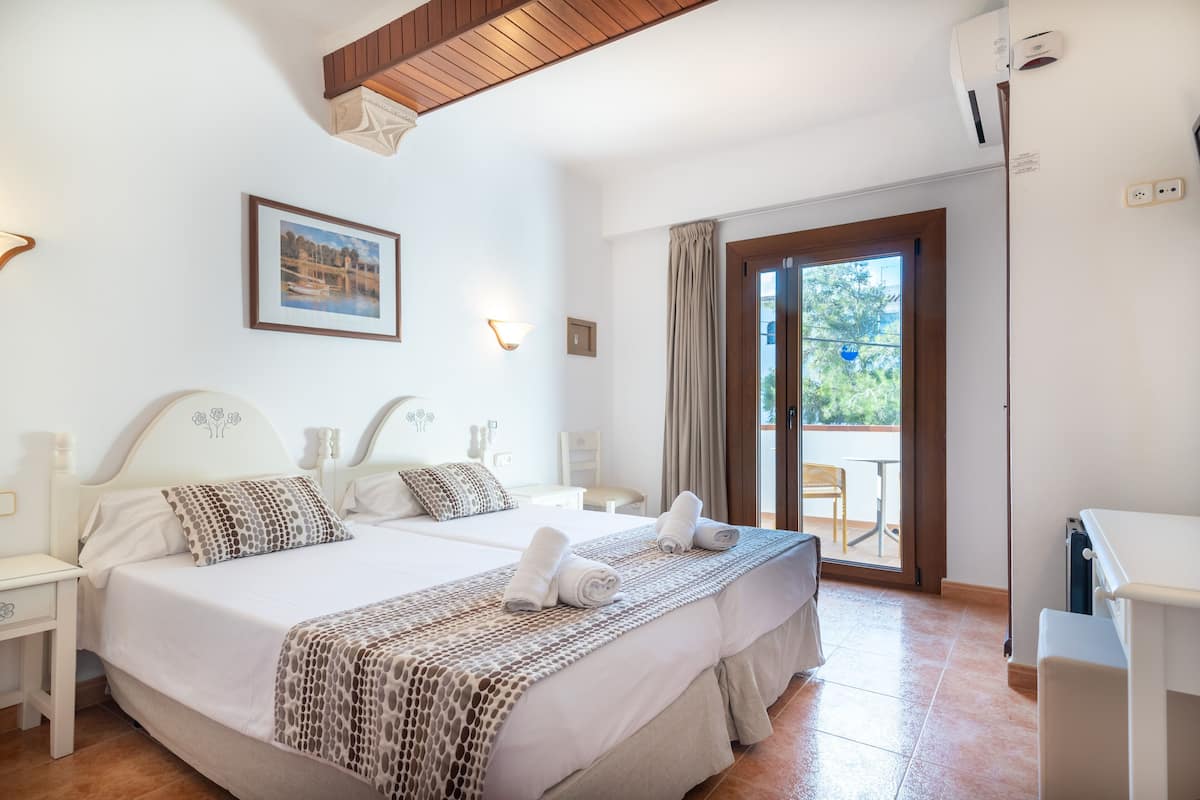 A double room with a bed, bedside tables, a desk, and a view of the outdoors.