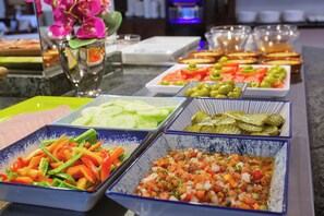 A buffet with various dishes including sliced cucumbers, olives, and a salsa dish. - Hotel Ses Puntetes (Santanyi)