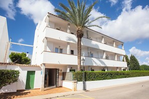 A multi-story building with balconies, a palm tree, and a clear sky. - Hotel Ses Puntetes (Santanyi)
