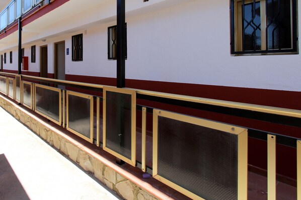 Un edificio con fachada roja y blanca, base de piedra y varios ventanales con marcos negros.