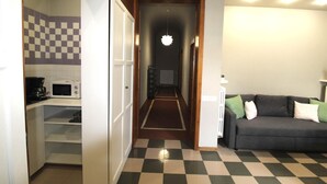 Un espacio habitable compacto con kitchenette, un sofá y un piso a cuadros.