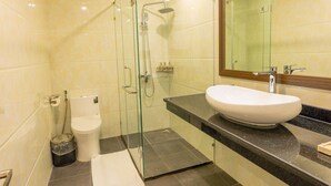 A modern bathroom with a glass-enclosed shower, a white sink, and a large mirror. - Viktor Legends Hotel (Mong Cai)