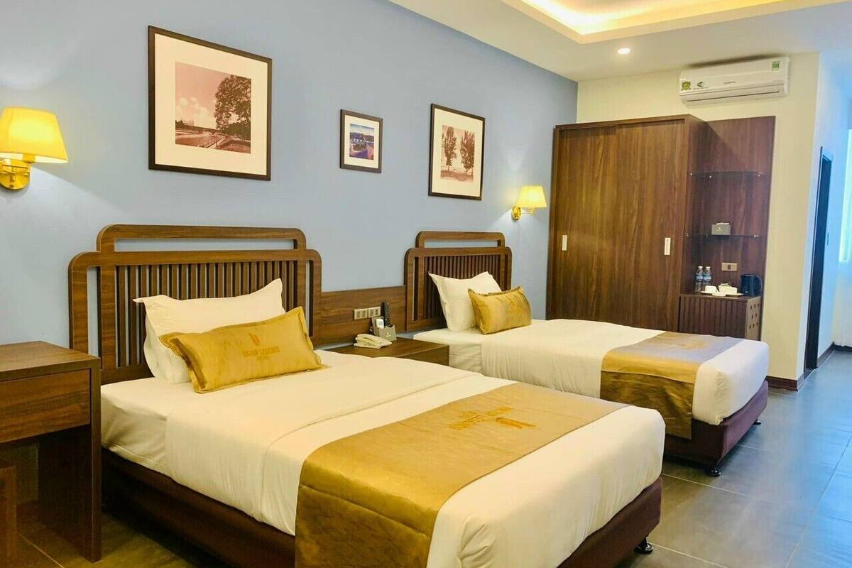 Een hotelkamer met twee bedden, houten hoofdeinden en een kledingkast.