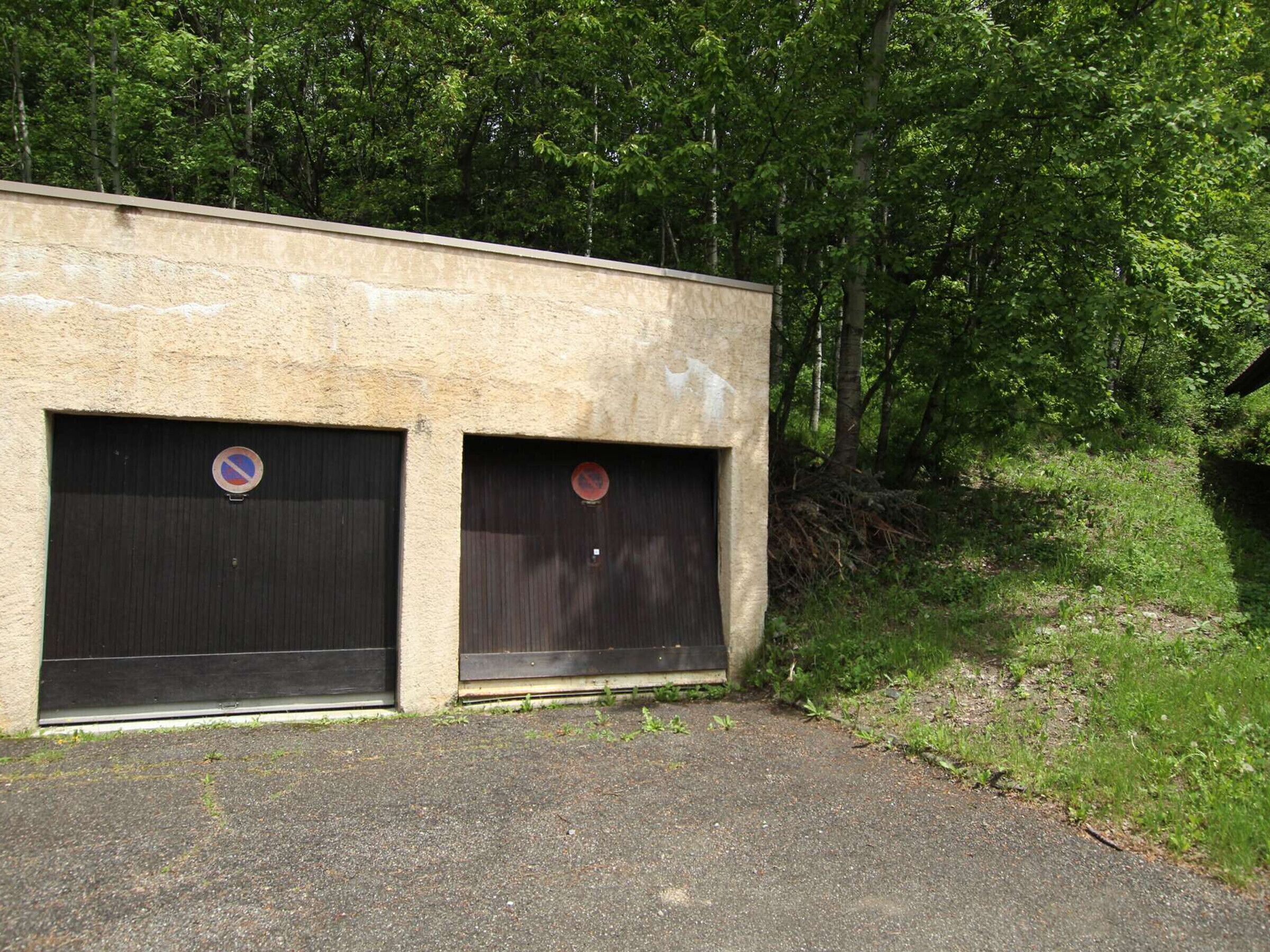 En bygning med to lukkede garageporte, hver med et forbudt parkering-skilt.