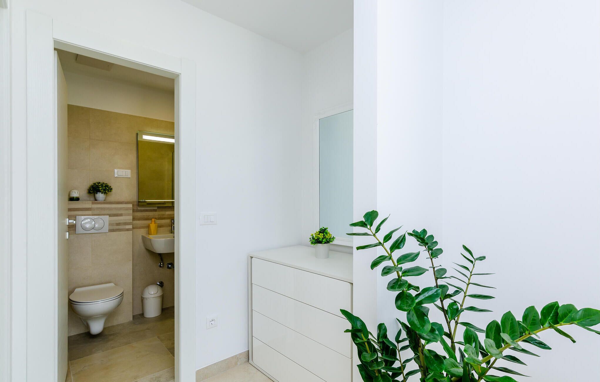 A modern bathroom with a toilet, sink, and mirror.