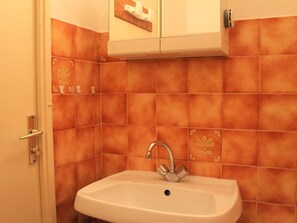 A bathroom with a white sink, a silver faucet, and orange-tiled walls. - Cozy Studio with Balcony, Sleeps 6, Close to Ski Lifts and Shops, Vars Les Claux (Vars)