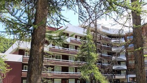A multi-story hotel with balconies, surrounded by trees.