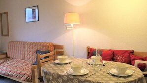 A cozy room with a bed, a table set for tea, and a lamp.