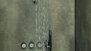 A modern shower with multiple water jets against a textured wall. - Appartement Hotel Royal (Bad Fuessing)