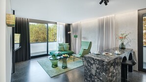 A modern living room with a green sofa, a marble coffee table, and a dining area with a table and chairs. - Appartement Hotel Royal (Bad Fuessing)