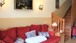 Un salon chaleureux avec un canapé en bois, une petite table, une lampe et un escalier.