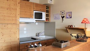 Une cuisine avec des meubles de rangement en bois, un four à micro-ondes, un évier et une cuisinière.