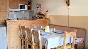 Une cuisine chaleureuse avec des meubles en bois, un four à micro-ondes et un coin repas agrémenté de chaises et d'une table.