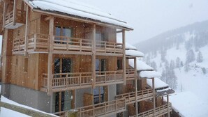 Un chalet en bois doté de plusieurs balcons et dont le toit est recouvert de neige.