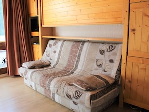 Um interior em madeira com um sofá-cama, cortinas e um armário de madeira.